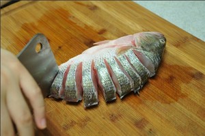 將鱸魚清洗干凈，從脊椎處切斷至腹部，腹部保留1cm左右不要切斷。