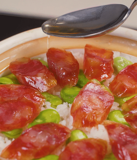 大米出現(xiàn)小孔時(shí)開(kāi)蓋放香腸，往鍋邊淋入少許油，再燜煮8~10分鐘左右。